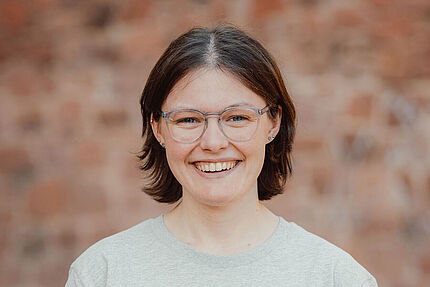 Porträt einer jungen Frau mit Brille. Sie trägt ein graues Shirt des Jungen ADFC und lächelt in die Kamera.